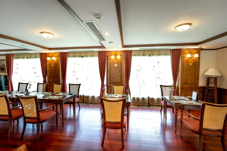 the dining area has wooden tables and chairs, an arched window and glass curtains