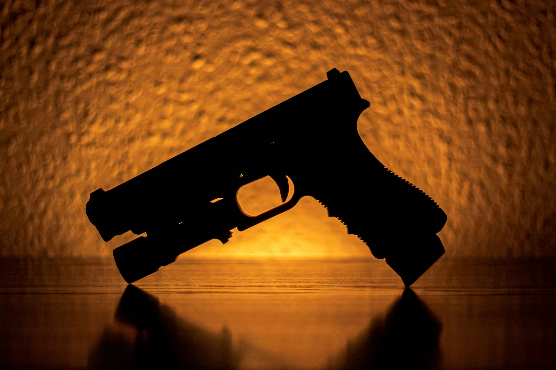 a close up of a gun on a table, an album cover, by Carey Morris, pixabay, silhouette, emergency countermeasures, profile picture 1024px, iridescent technology and weapon