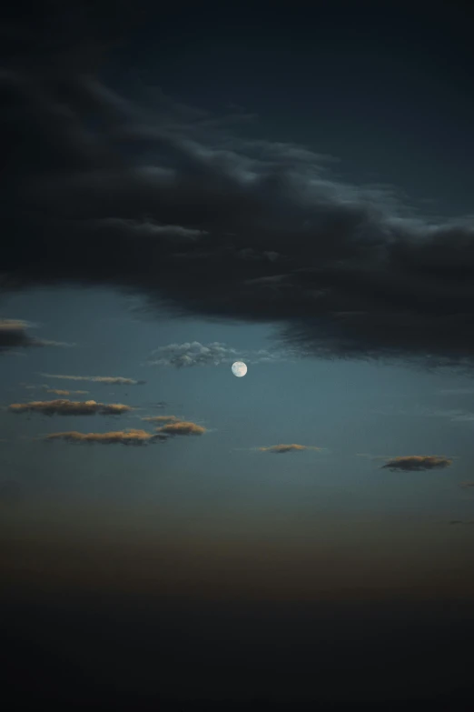 a full moon in the sky with a dark cloud