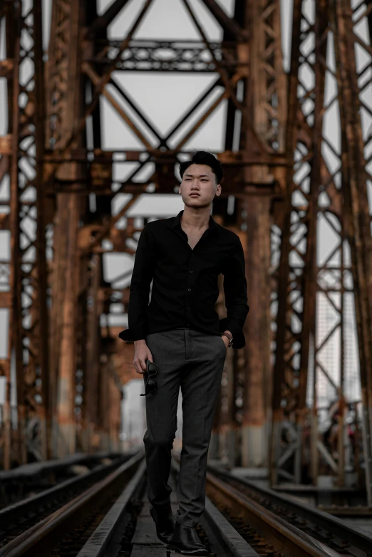 a man standing on top of a train track, an album cover, inspired by Victor Wang, pexels contest winner, standing with a black background, on a bridge, asian human, well dressed