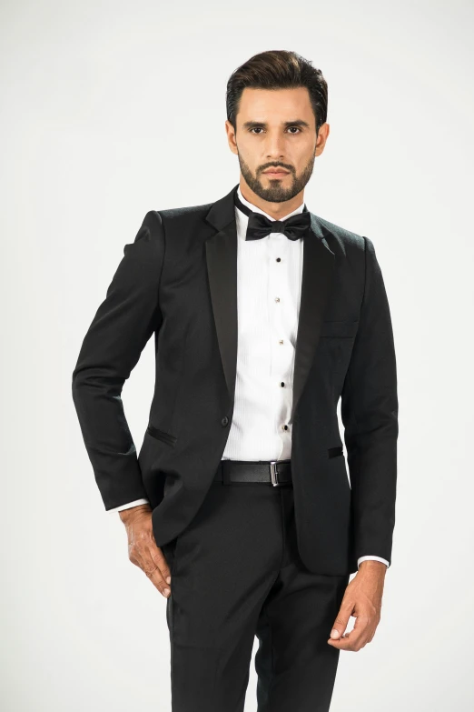 a young man wearing a tuxedo, posing in black suit