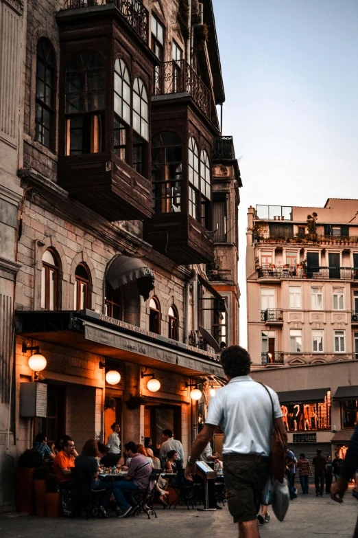 a group of people walking down a street next to tall buildings, a picture, renaissance, istanbul, beautifully lit buildings, old shops, 2019 trending photo