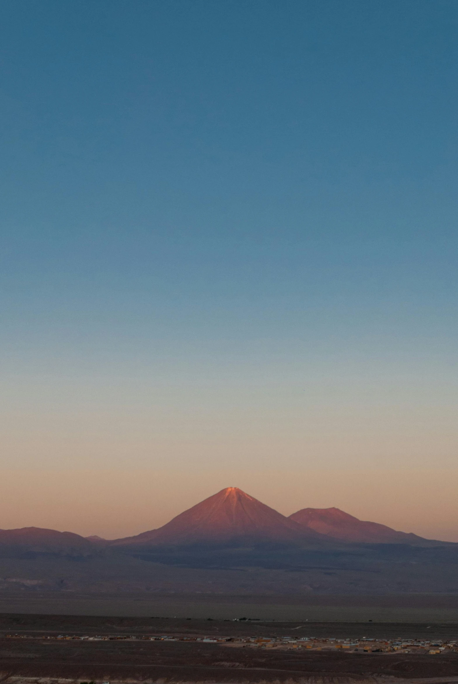 a lone white horse grazes near the mountain