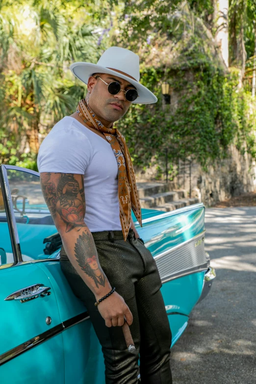 a man wearing a hat and glasses sitting on the back of an antique car