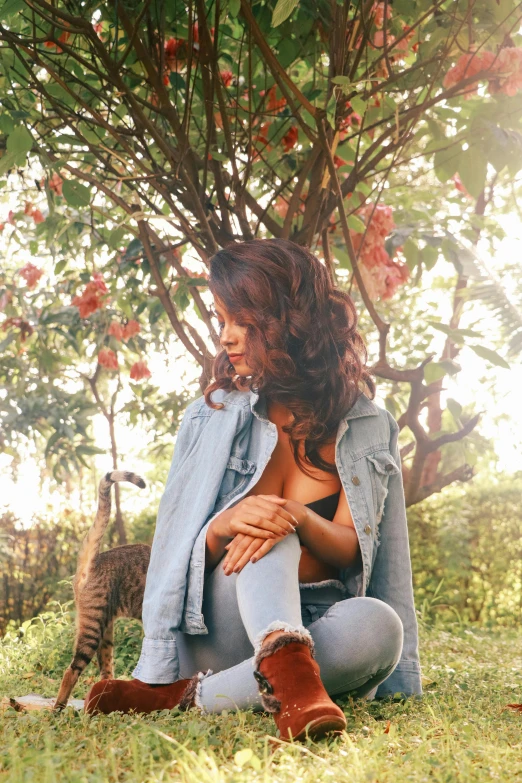 an image of a woman in jeans sitting under a tree