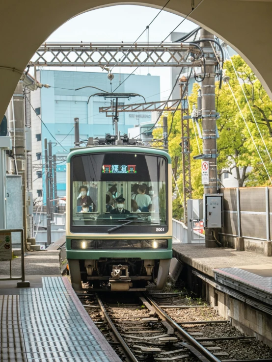 a green train pulling into a train station, unsplash, sōsaku hanga, slide show, street tram, 3/4 front view, 🚿🗝📝