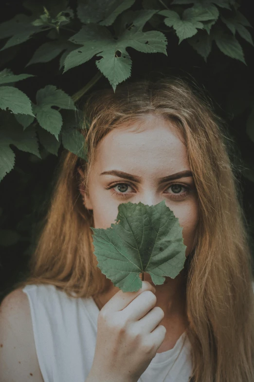 a woman holding a leaf in front of her face, pexels contest winner, blonde hair and large eyes, photo of a model, lush and green, photography portrait 4 k