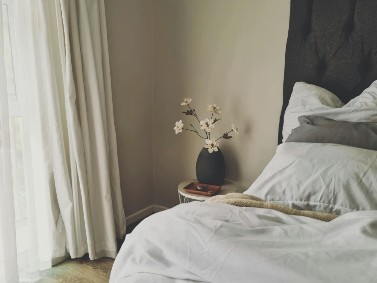 bed with white sheets and a white flower vase