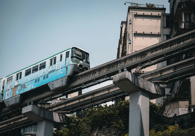 a blue train is going through an industrial area