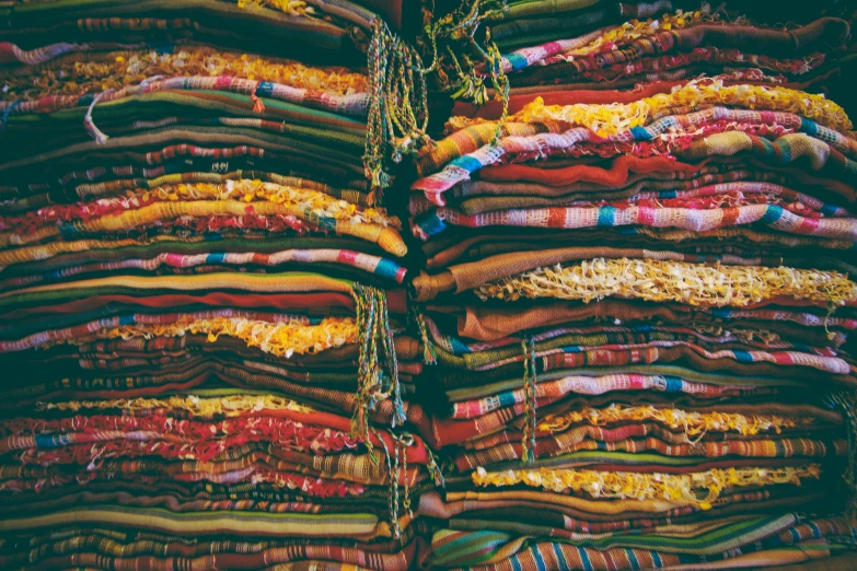 a bunch of blankets stacked on top of each other, by Daniel Lieske, trending on unsplash, maximalism, middle eastern style vendors, embroidered robes, deep lush vivid colors, 🦩🪐🐞👩🏻🦳