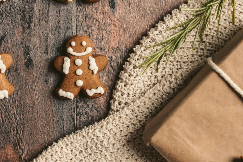 a couple of ginger cookies sitting on top of a wooden table, inspired by Ernest William Christmas, trending on pexels, crochet skin, background image, presents, he is happy