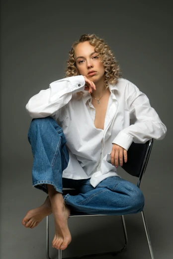 a woman sitting on a chair in a white shirt, by irakli nadar, trending on pexels, renaissance, curly blond, baggy jeans, portrait sophie mudd, wearing a shirt