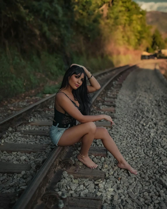 a women sitting on the tracks near some train tracks