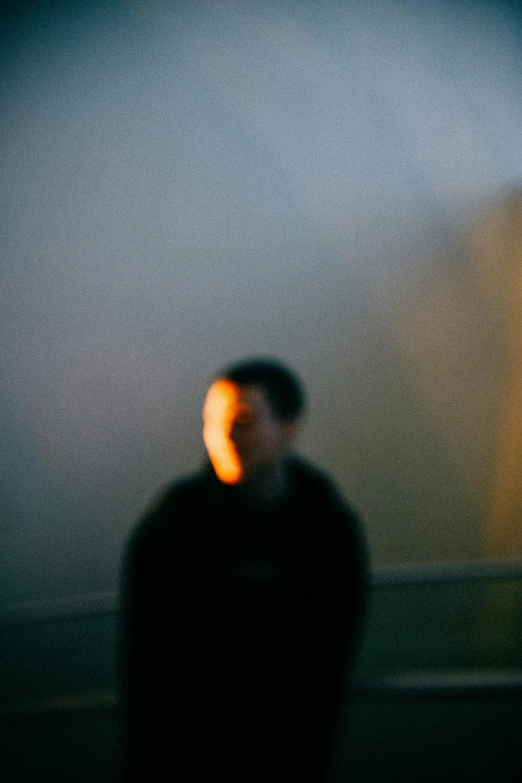 a blurry image of a man standing in front of a wall, by Adam Chmielowski, ambient amber light, shigeto koyama, a face, overexposed