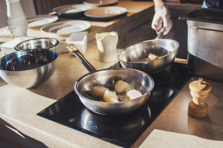 a person in a kitchen preparing food on a stove, by Daniel Lieske, pexels, pan and plates, at the counter, “ iron bark, school class