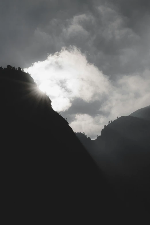 the sun shines through the clouds over the mountains, pexels contest winner, light and space, grey, silhouette :7, lauterbrunnen valley, black