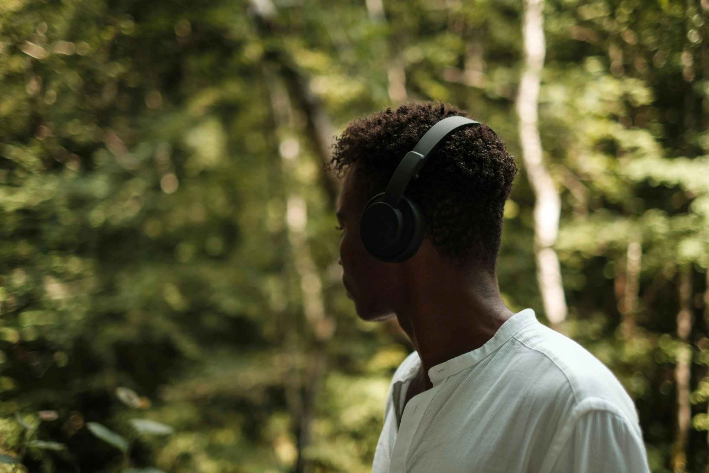 a man standing in the woods wearing headphones, pexels contest winner, profile view perspective, afternoon hangout, man is with black skin, a round minimalist behind