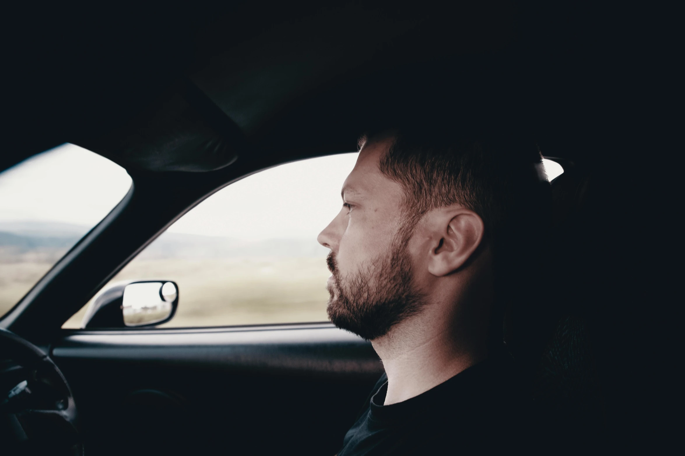 a man sitting in the driver's seat of a car, an album cover, by Hallsteinn Sigurðsson, unsplash, profile image, shia labeouf, profile picture, long distance photo