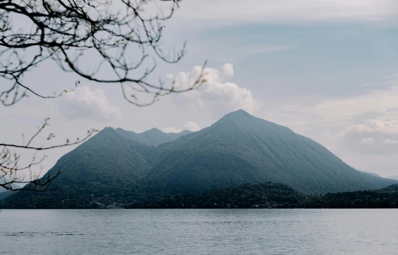 there is a mountains on the water that looks like it has clouds