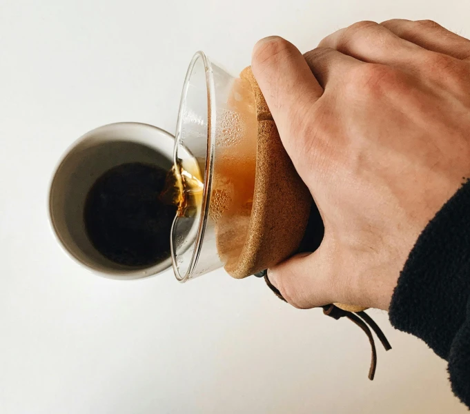 a person in black jacket drinking a glass of beer