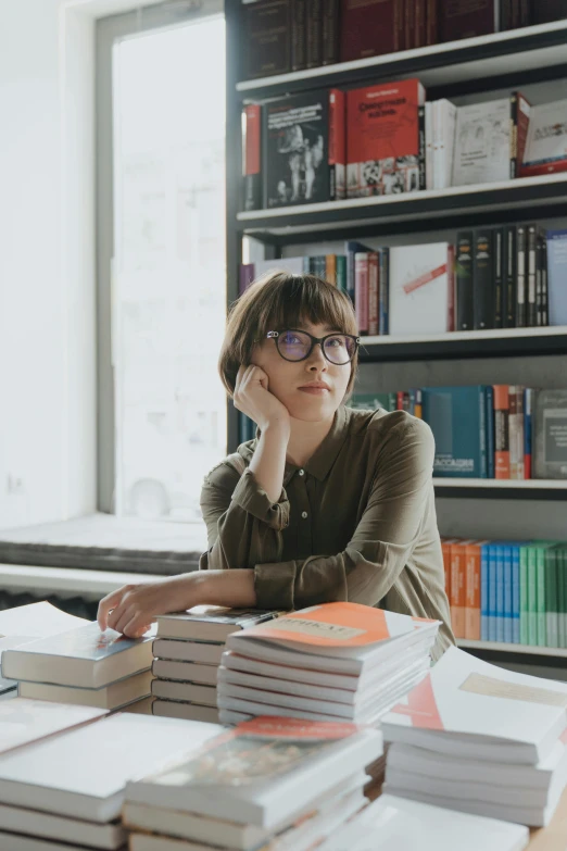 a woman sitting at a table with lots of books, altermodern, wearing round glasses, ignant, yulia nevskaya, proud looking away