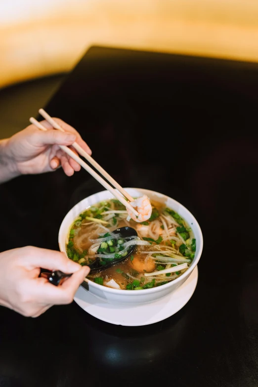 a person eating a bowl of soup with chopsticks, daily specials, square, sitting down, sparkling