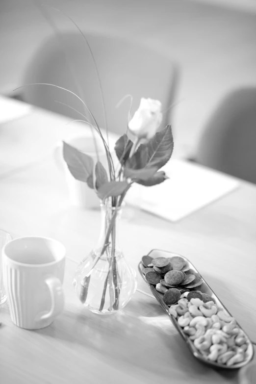 flowers and nuts are sitting on a table in front of an empty mug