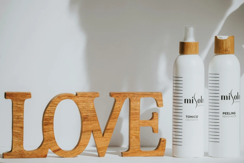 a couple of bottles of lotion sitting next to each other, by Olive Mudie-Cooke, pexels contest winner, flowing lettering, in a white boho style studio, wooden art toys on base, minimalist rule of thirds