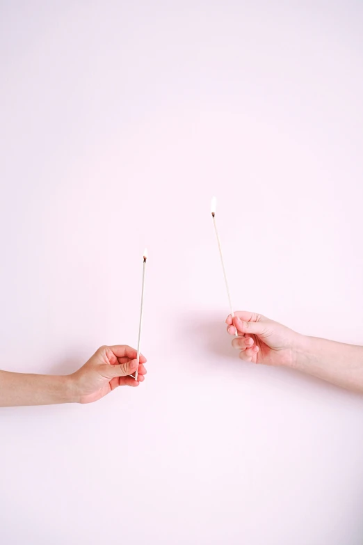 a couple of people that are holding sticks in their hands, an album cover, by Rachel Reckitt, trending on pexels, conceptual art, white candles, iv pole, dueling, white and pink cloth