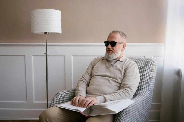 a man sitting in a chair reading a book, unsplash, hyperrealism, wearing shades, dementia, a very macular woman in white, man in his 40s