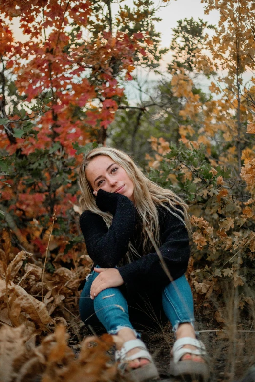 a woman sitting on top of a pile of leaves, a portrait, unsplash contest winner, wearing jeans and a black hoodie, sydney sweeney, headshot profile picture, fall colors