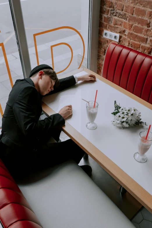 a man sitting at a table in a restaurant, an album cover, trending on unsplash, neo-romanticism, asleep, tuxedo, non binary model, spilled milk