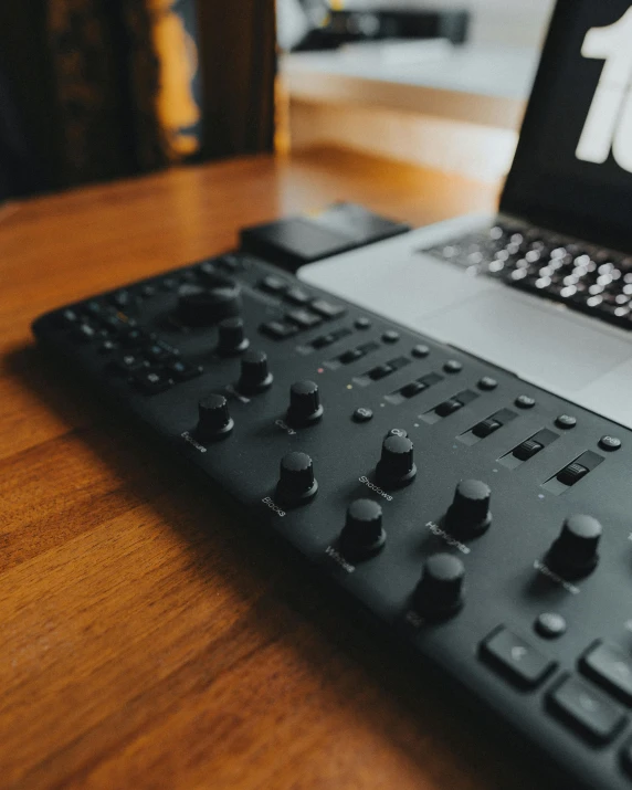 a laptop computer sitting on top of a wooden table, an album cover, by Adam Rex, unsplash, control panels, controller, all black matte product, knobs