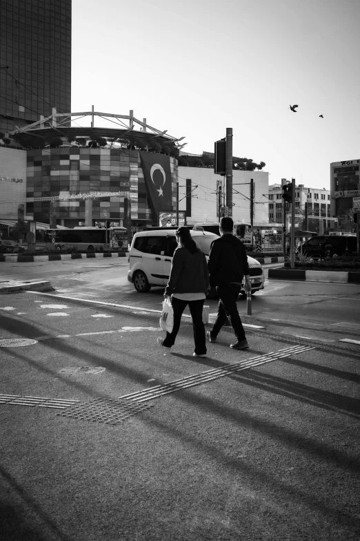 a couple of people walking across a street, by Nabil Kanso, intersection, monochrome:-2, cold mood, ying and yang