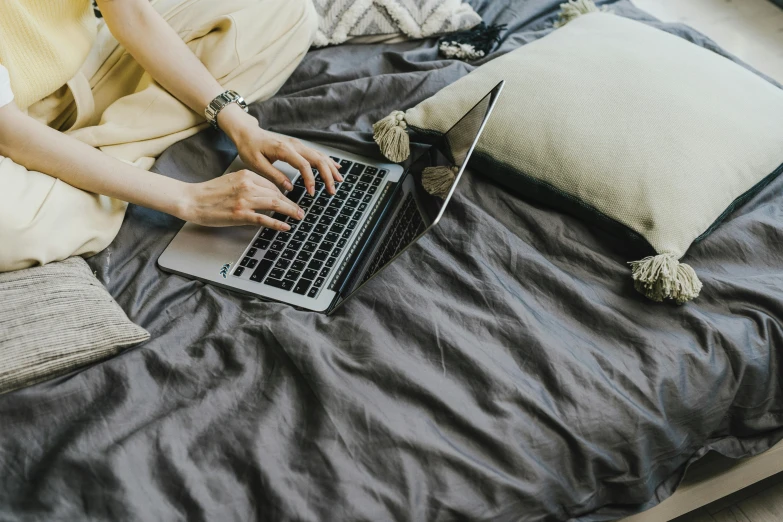 a woman sitting on a bed using a laptop computer, trending on pexels, gold linens, avatar image, background image, flatlay