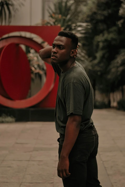 a man looking off to his right in front of a red sculpture