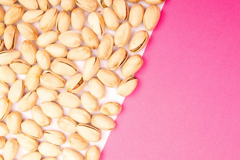 a pile of pistats on a pink and white background, trending on pexels, peanuts, background image, cosmopolitan, middle of the page