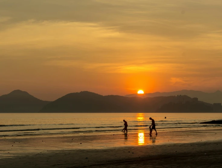 a person on a beach and some people watching a sunset