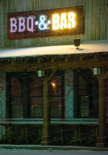 a building with a sign that says bbq and bar, a portrait, perfect lighting in a snow storm, taken in silver dollar city, billboard image