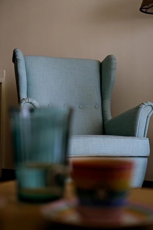 a light blue arm chair and glass cup on the table