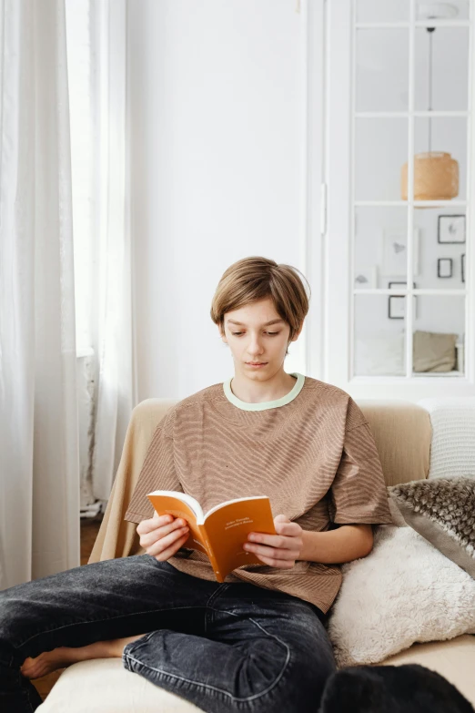 a woman sitting on a couch reading a book, a cartoon, pexels contest winner, wearing a light shirt, wearing an orange t-shirt, androgynous person, girl with brown hair