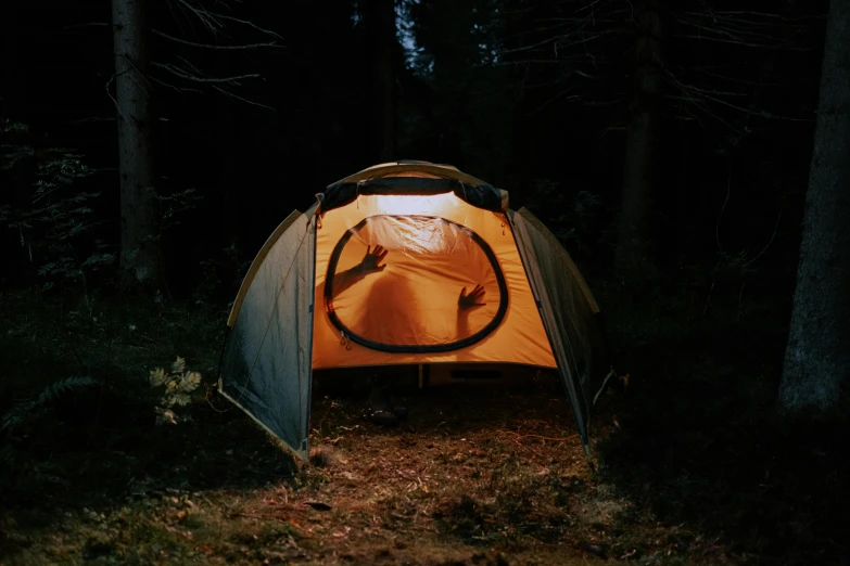 a tent sitting in the middle of a forest, holding up a night lamp, orange halo, ignant, exterior shot