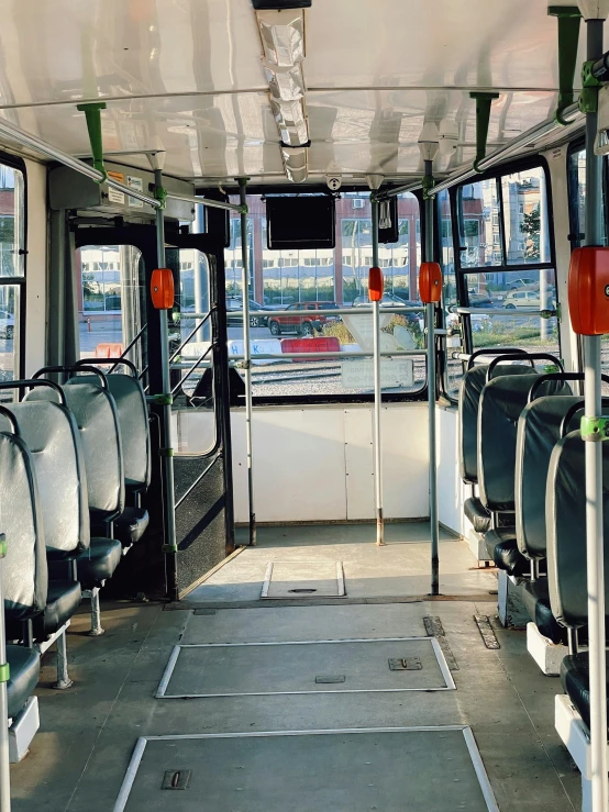 a bus filled with lots of empty seats, with a city in the background, thumbnail, back - view, full daylight