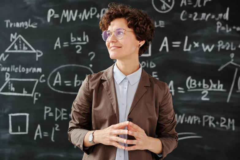 a woman wearing glasses standing in front of a blackboard, by Adam Marczyński, pexels, academic art, neri oxman, wearing a suit and glasses, thiago lehmann, teacher