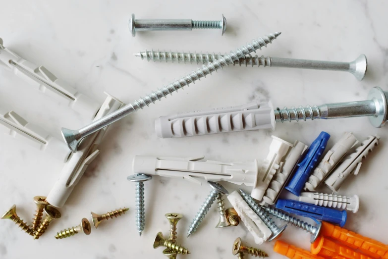 a bunch of screws sitting on top of a table, white wall coloured workshop, bright construction materials, all teeth, detailed product image