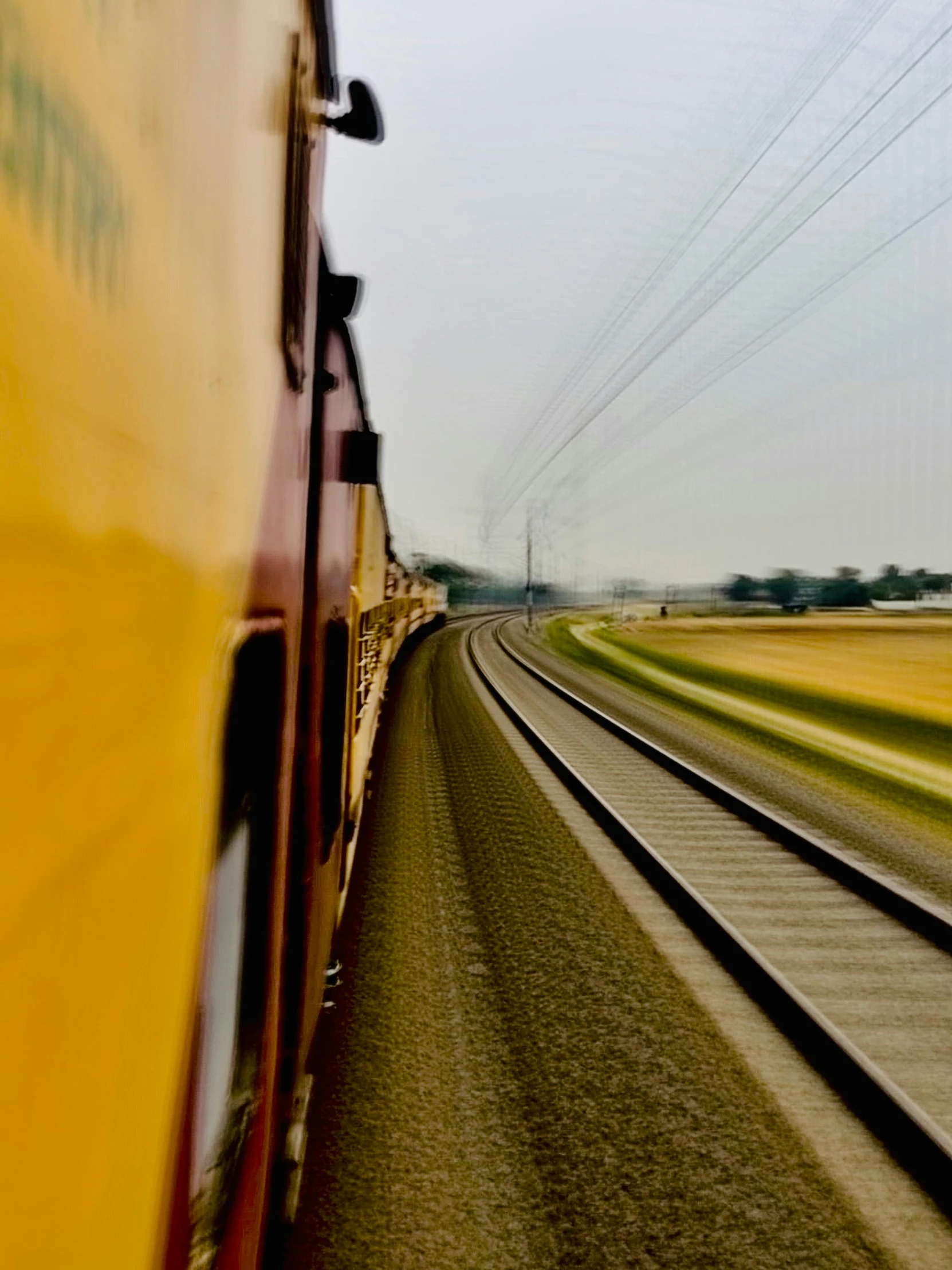 a yellow train traveling down train tracks next to a field, a picture, by Jan Tengnagel, helmet view, low quality photo, instagram story, dsrl photo