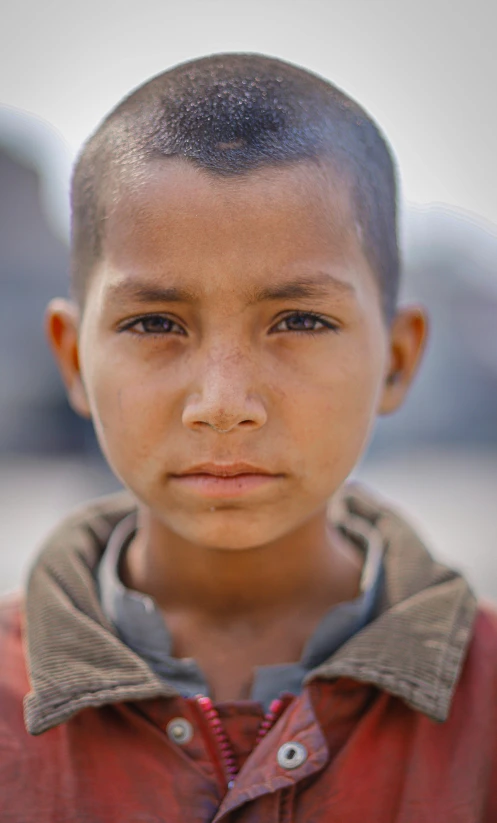 a young boy in a red jacket looking at the camera, an album cover, inspired by Steve McCurry, pexels contest winner, light-brown skin, nepal, headshot photo, profile picture 1024px