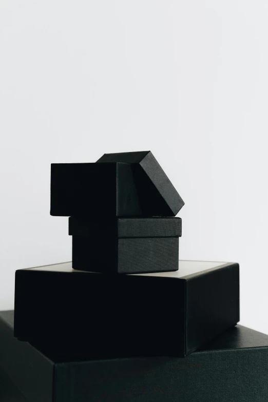 three black boxes stacked on top of each other, an abstract sculpture, trending on unsplash, professional product photo, high picture quality, black hat, made of rubber