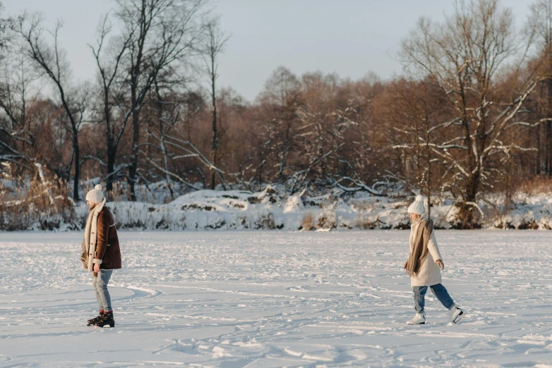 a couple of people walking across a snow covered field, pexels contest winner, in a park and next to a lake, beautiful girls, cardboard, rollerskaters