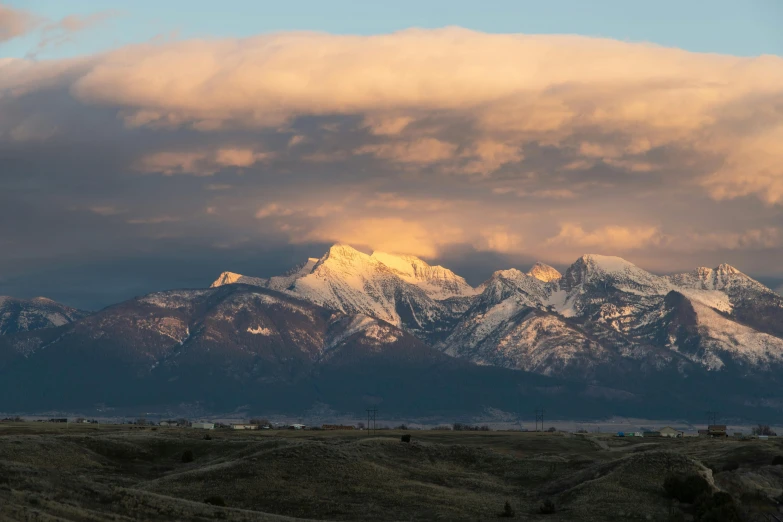 the clouds are flying over the snowy mountain tops